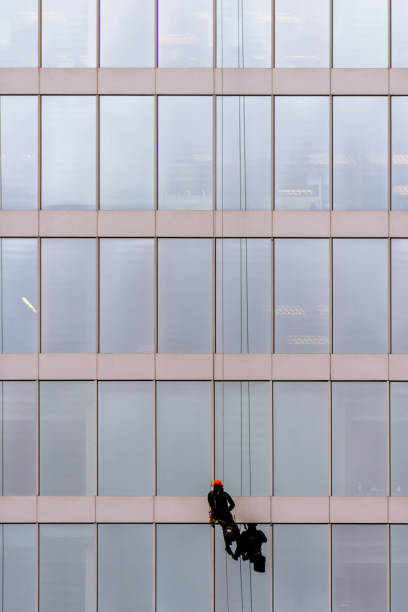 istock man in a red helmet hanging on a long rope on a high-rise office building 891784814