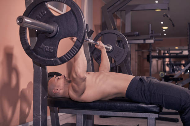 istock one bodybuilder, Bench Press, weights bar, gym indroors. 891795160