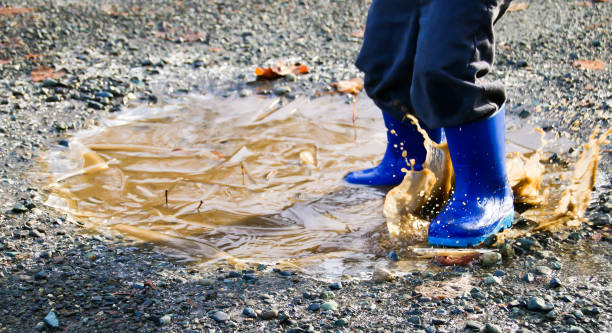 istock Close up of childs boots in puddle 891798092