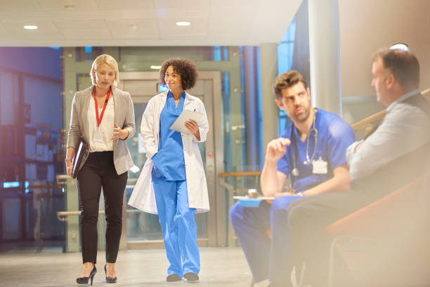 doctor listening to sales rep in hospital corridor - female nurse nurse scrubs female doctor imagens e fotografias de stock