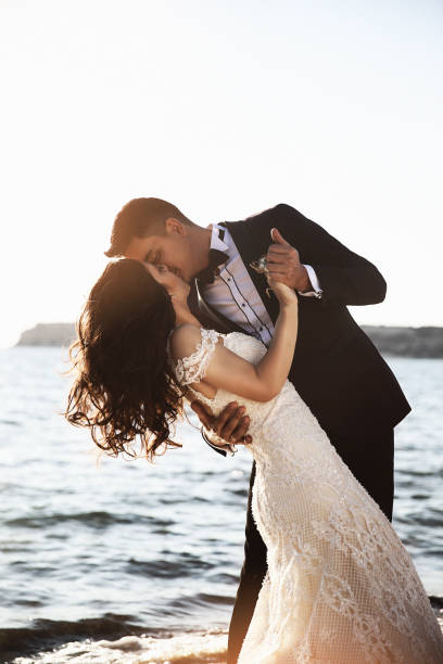 新郎新婦には、素晴らしい夕日をお楽しみいただけます。 - wedding beach groom bride ストックフォトと画像