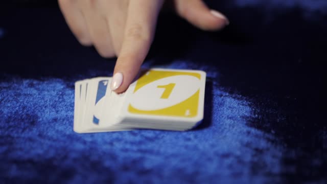 Woman unfolds cards on a blue table in the casino. Slow motion. Uno game