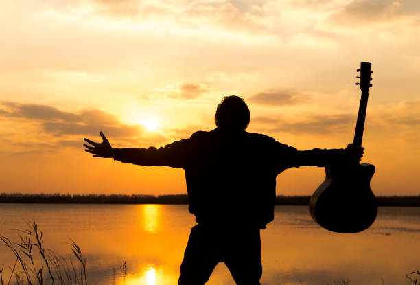 istock silhouette of men with guitar against sunset sky 891843386