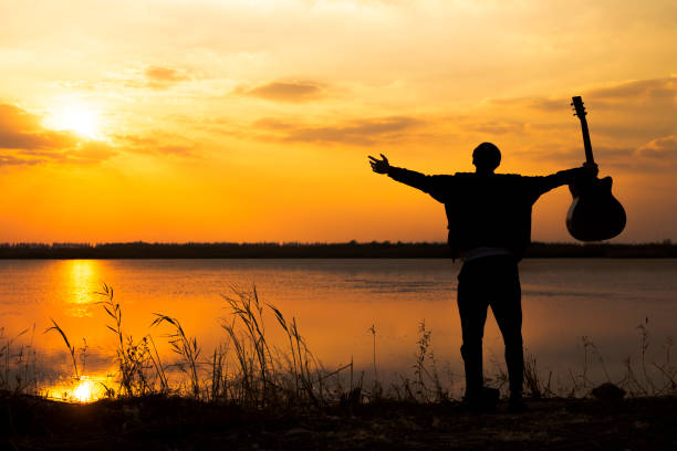 istock silhouette of men with guitar against sunset sky 891843390