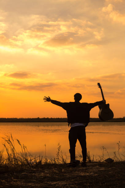 istock silhouette of men with guitar against sunset sky 891843392