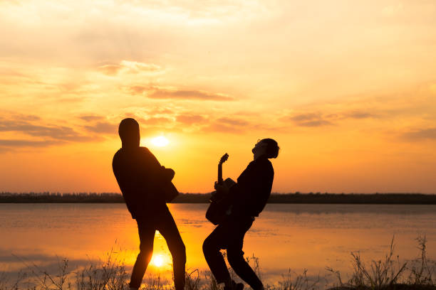 istock silhouette of men playing guitar against sunset sky 891843690