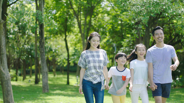 Asian parents & kids walking outdoors on summer weekend & laughing stock photo