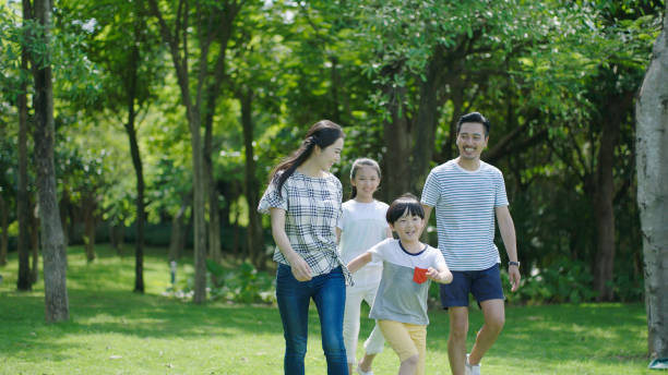 istock Asian parents & kids walking outdoors on summer weekend & laughing 891858786