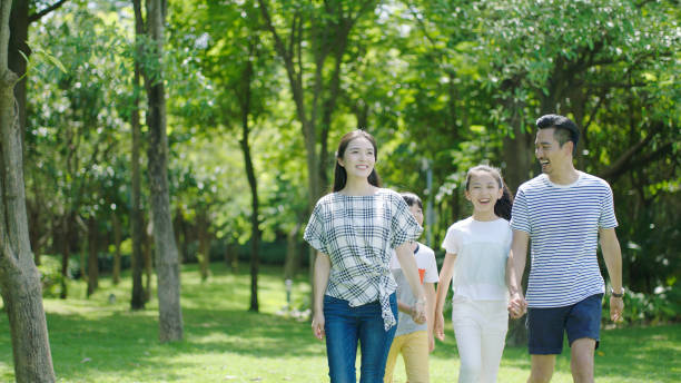istock Asian parents & kids walking outdoors on summer weekend & laughing 891858790