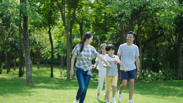 istock Asian parents & kids walking outdoors on summer weekend & laughing 891858880