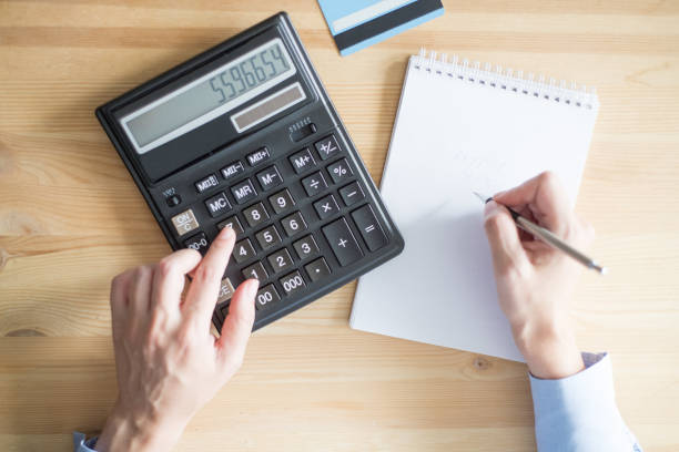 istock Closeup of Person Using Calculator and Writing 891872542