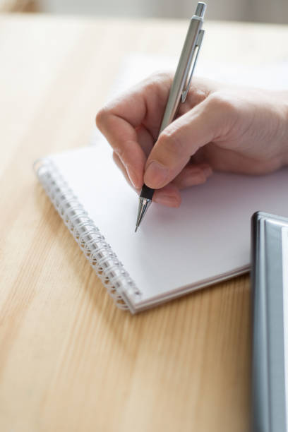 istock Closeup of Person Writing in Notebook 891872590