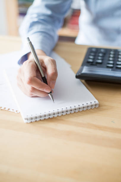 istock Closeup of Woman Using Calculator and Writing 891872602