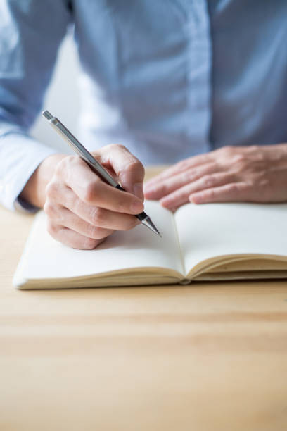 istock Closeup of Woman Writing in Notebook at Table 891872624