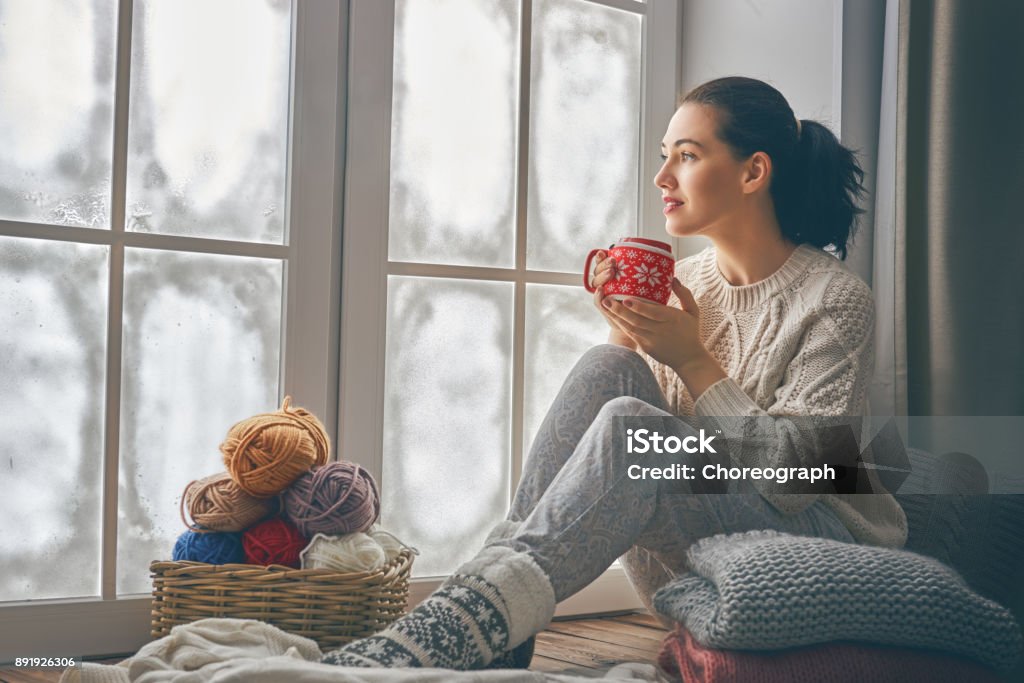 mujer sentada junto a la ventana - Foto de stock de Invierno libre de derechos