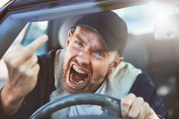 istock Furious man driving yells, making obscene gesture 891928844