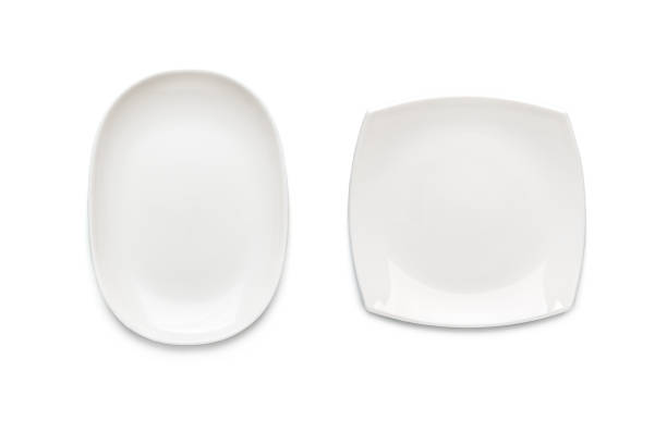 Two white plates of different shapes on a white background. View from above. Isolated. stock photo