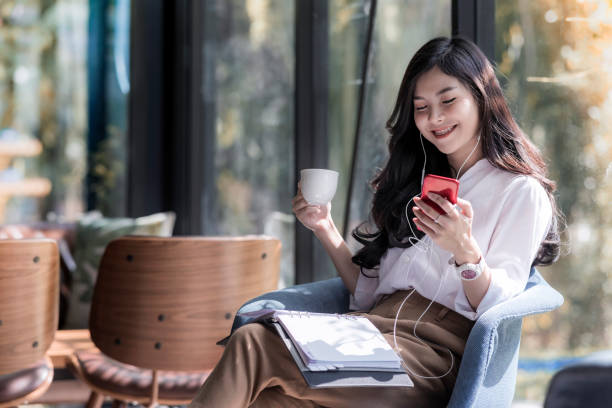 커피와 커피가 게에서 그녀의 휴대 전화에서 듣는 음악의 아름 다운 젊은 아시아 여자 들고 컵의 샷 - smart phone china mobile phone asia 뉴스 사진 이미지