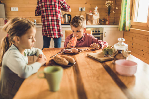 istock Little boy drinking fresh juice during breakfast time at dining table. 891937148
