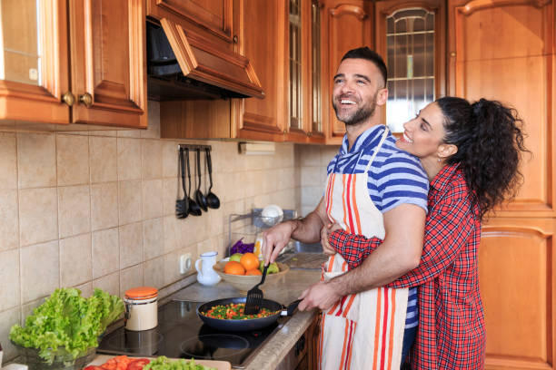 istock Couple embracing and making dinner at home 891940004