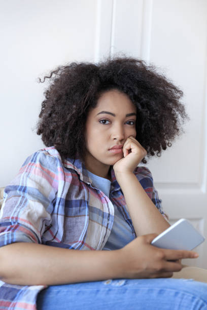 istock Young woman sitting at home and using smart phone 891940162
