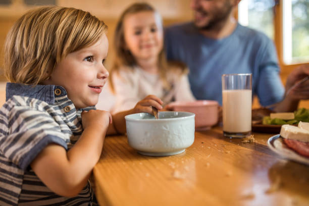 istock Cute little boy eating breakfast with his family at dining table. 891942604