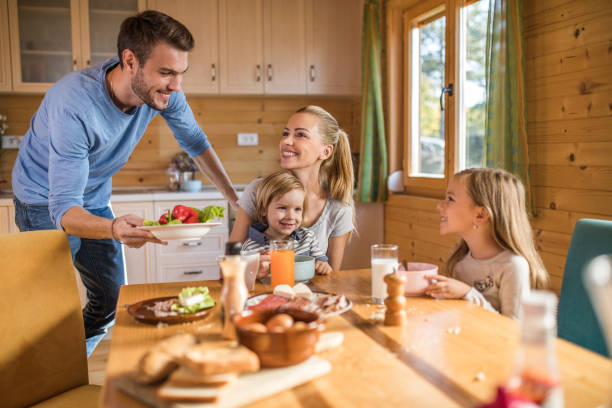 istock Young smiling parents and their small kids having a meal at dining table. 891945184
