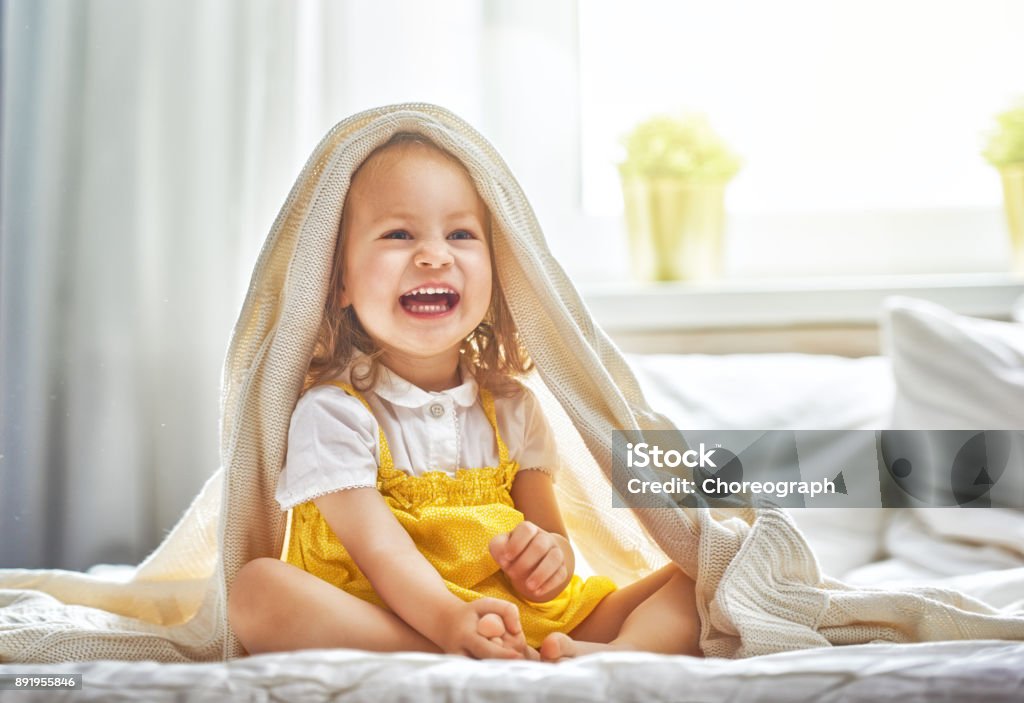 baby girl on the bed Beautiful smiling cute baby girl on the bed in the room at home. Happy child laughing. Baby - Human Age Stock Photo