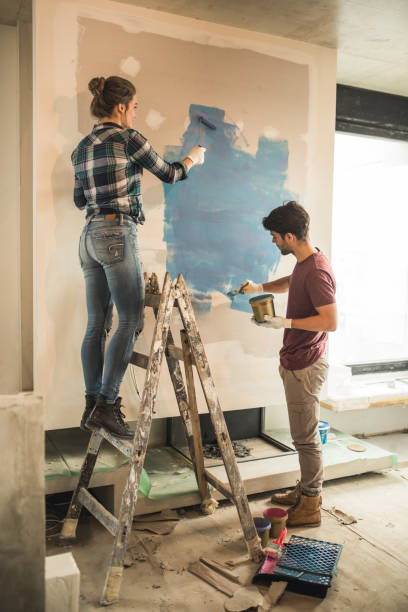 full length of young couple painting their walls during home renovation process. - repairing apartment home improvement painting imagens e fotografias de stock