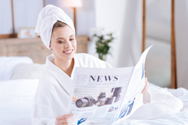 istock Pleasant woman in bathrobe reading news 891972472