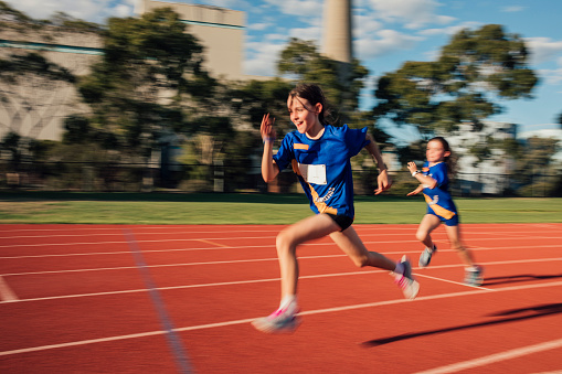 Two girls are racing each other on the running track at athletics club.