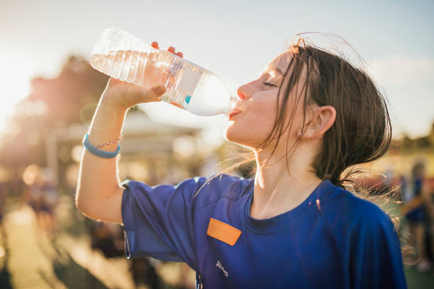 Water Is The Fuel For Exercise! Little girl is taking a big gulp of water from a bottle during athletics club. one girl only stock pictures, royalty-free photos & images