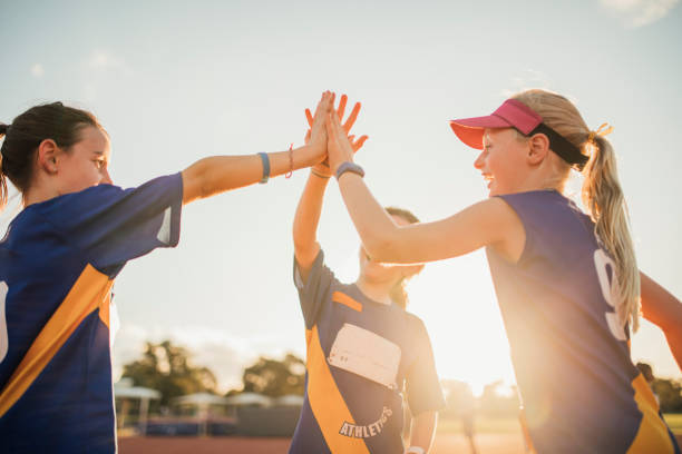 Team Celebration In Athletics Club Three girls are high-fiving after a race at athletics club. sports activity stock pictures, royalty-free photos & images