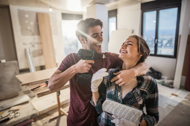 pareja juguetona divertirse con taladro mientras la renovación de su apartamento. - home improvement drill men house fotografías e imágenes de stock