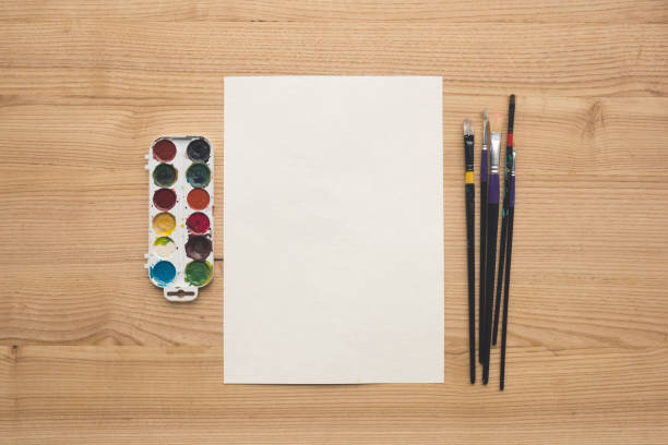 Top view of empty sheet of paper with watercolor paints and brushes
