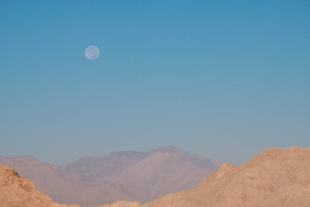 istock Landscape mountain image with the moon in clear blue sky background 891982138