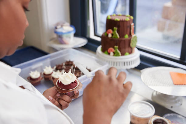 istock Black woman preparing food in a bakery, over shoulder view 892009458