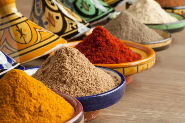 Diversity of Moroccan powder herbs in colorful ceramic tagines close up