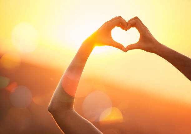 In love with the landscape Shot of an unidentifiable woman's hands making a heart shape over a sunset landscape touch of the sun stock pictures, royalty-free photos & images