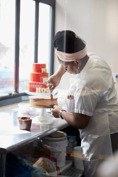 istock Young black woman frosting a cake at a bakery 892019046