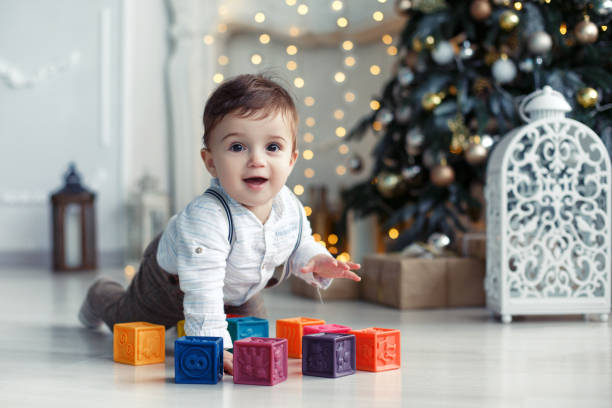 istock Cute little boy playing near the Christmas tree with colored cubes 892022302