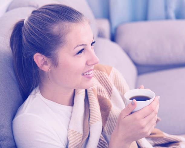 istock Young female is warming with tea and sitting in plaide 892039670