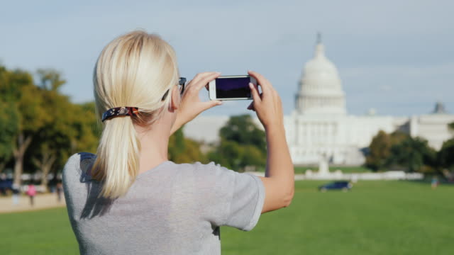 A woman tourist takes pictures of the Capitol building in Washington. Tourism in the USA concept