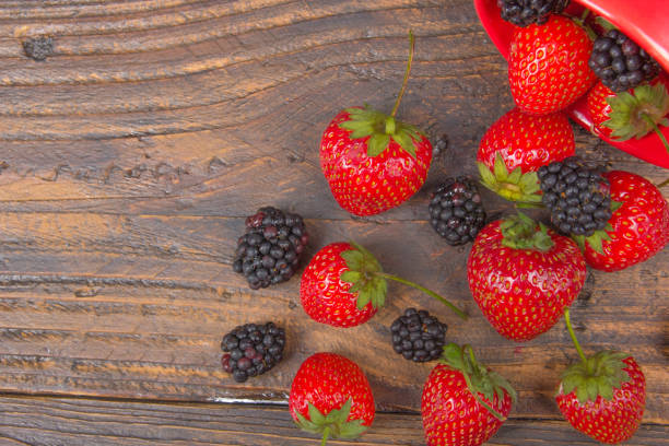 blackberries, strawberrieson wooden table background, spilled from a spice jar. antioxidants, detox diet, organic fruits. berries - raspberry table wood autumn imagens e fotografias de stock