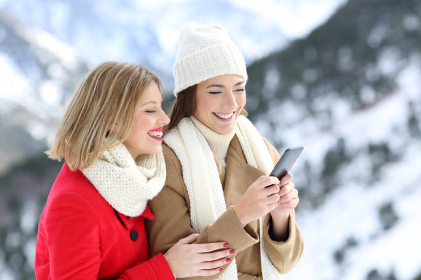 istock Two friends using a smart phone in winter in the mountain 892046816