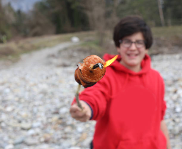 istock smiling boy with wurstel cooked on wooden stick and flame 892063050