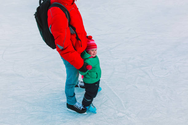 istock father and little daughter learning to skate in winter 892083048