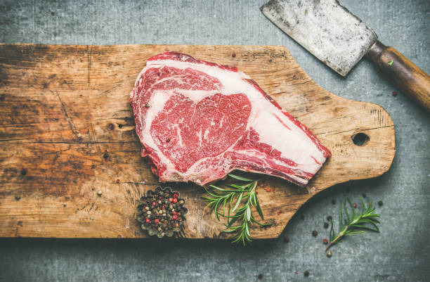 istock Raw beef steak rib-eye on board with seasoning and knife 892088462