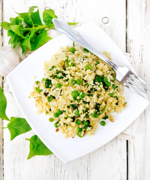 Couscous with spinach and green peas in plate on board top
