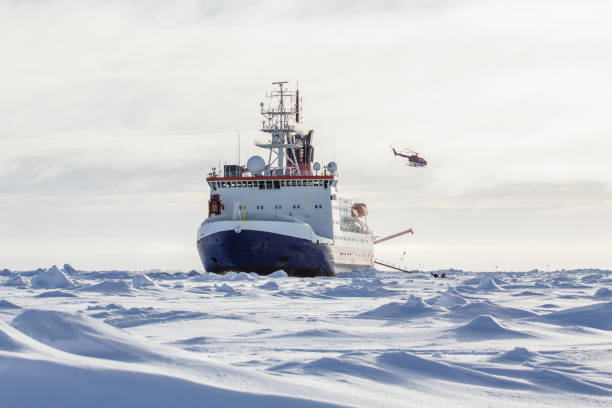 Research icebreaker and helicopter Research icebreaker docked to an ice floe and and a helicopter recently took off from the helideck while setting up an ice camp antarctic ocean photos stock pictures, royalty-free photos & images